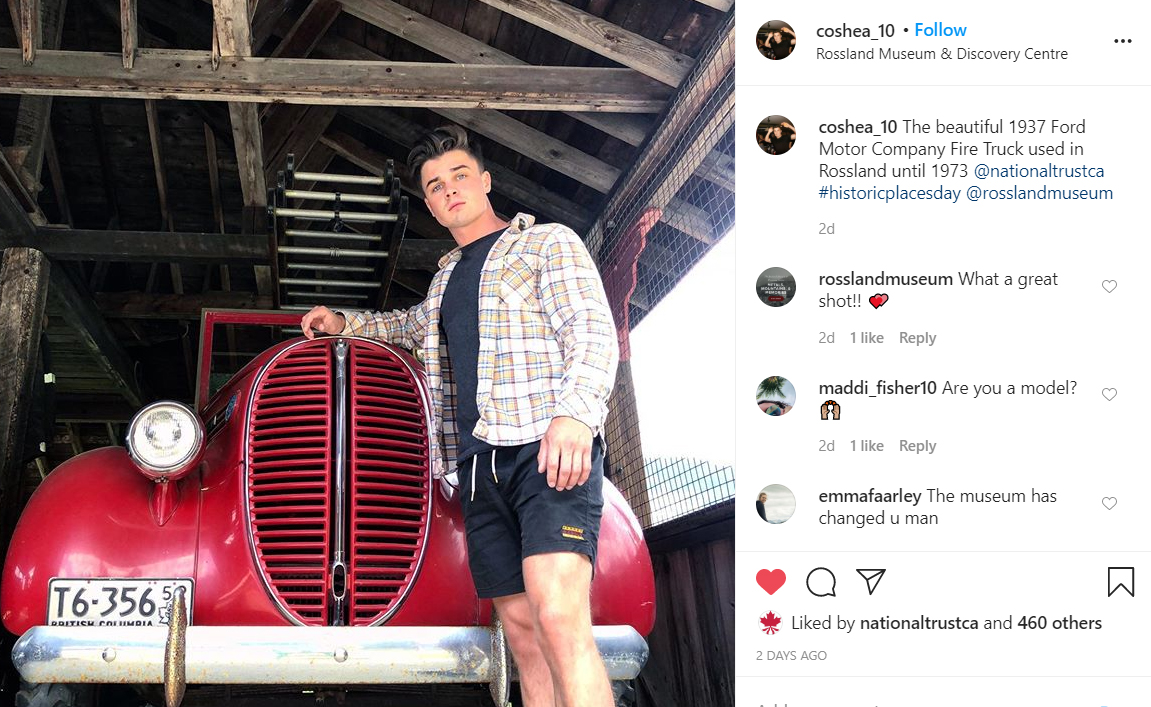 A young man poses with an old firetruck.